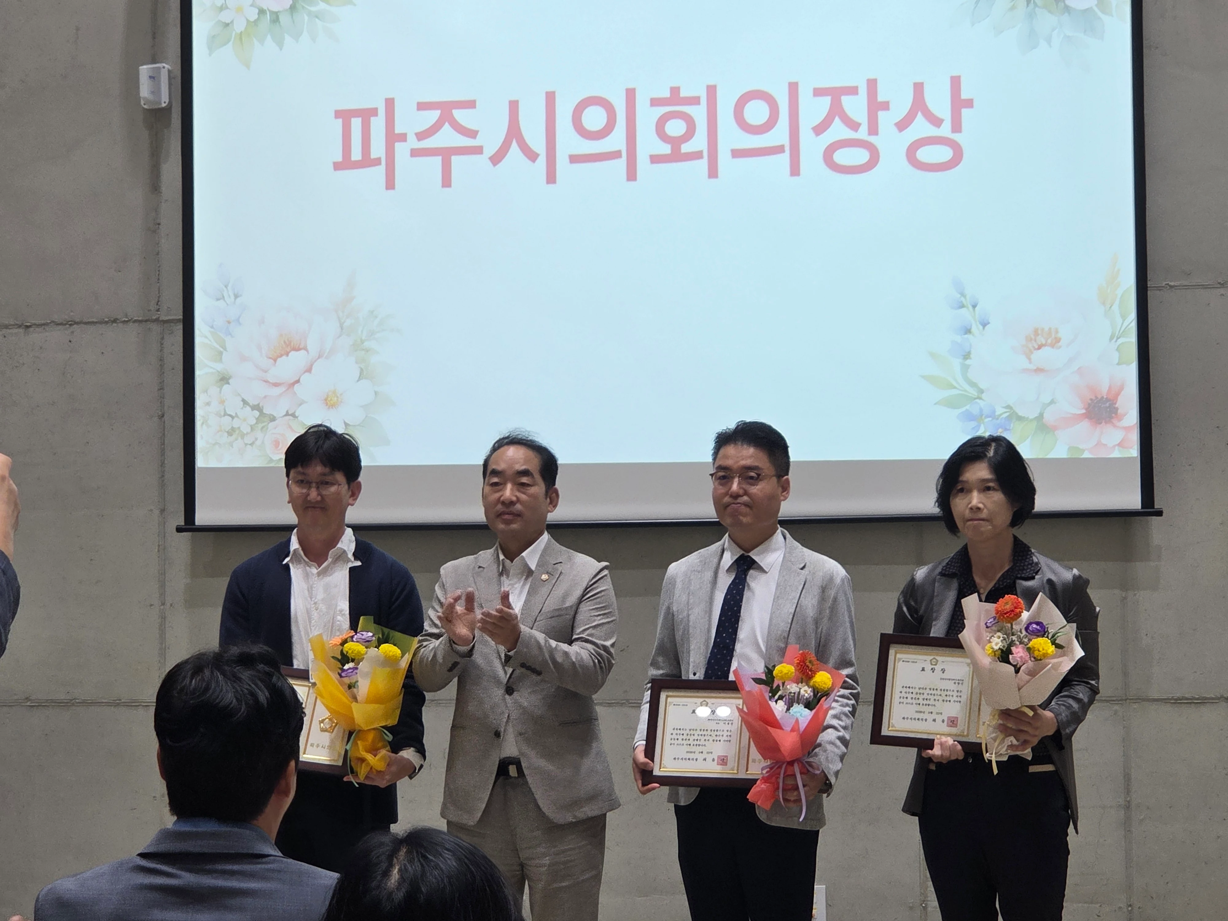 ‘파주시의회의장상’ 문구가 표시된 행사 화면 앞에서 수상자들과 행사 관계자가 표창패와 꽃다발을 들고 서 있다.